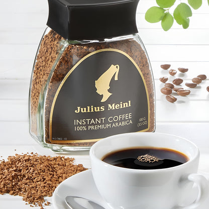 julius meinl instant kávé üvegben mellett csésze frissen főzött kávé, kávéval a háttérben
