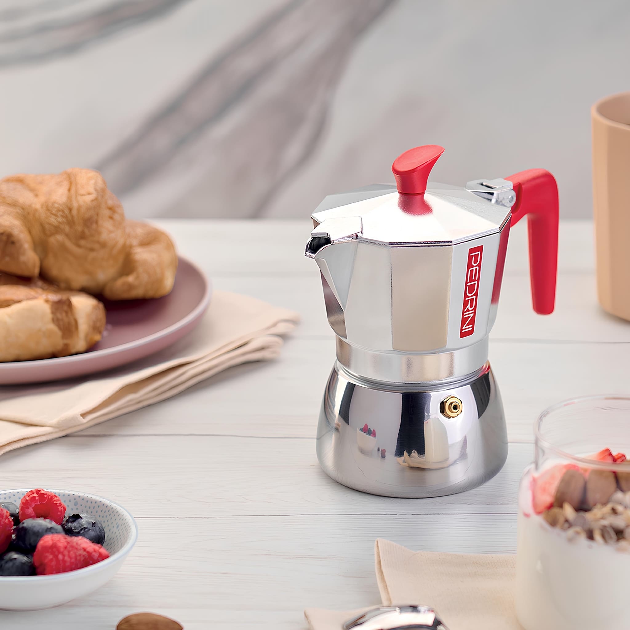 Pedrini Aroma Induction kotyogós kávéfőző mélykék színben egy reggeli asztalon, frissen főzött olasz eszpresszó csészék és péksütemények mellett.